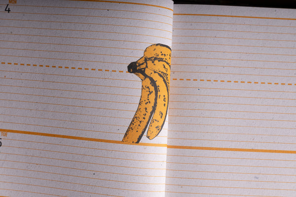 A close-up of lined notebook paper with a printed illustration of a yellow banana on the page.