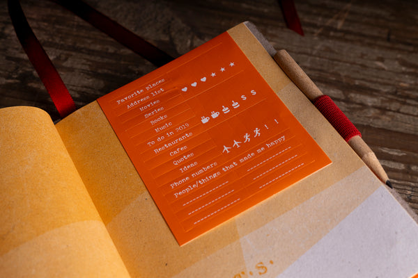 sticker-sheet-detail.jpg — Close-up of the orange sticker sheet included with the diary, with labels like favorite places, movies, and quotes