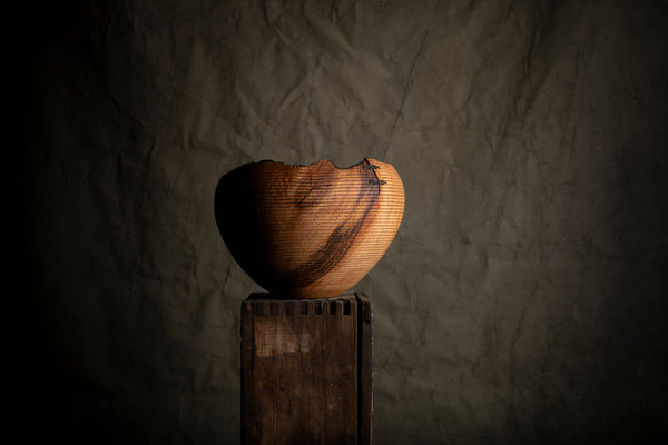 Wooden hand turned bowl from red oak on the dark green background. The bowl was created by Czech based artist Maalstrom.studio. 
