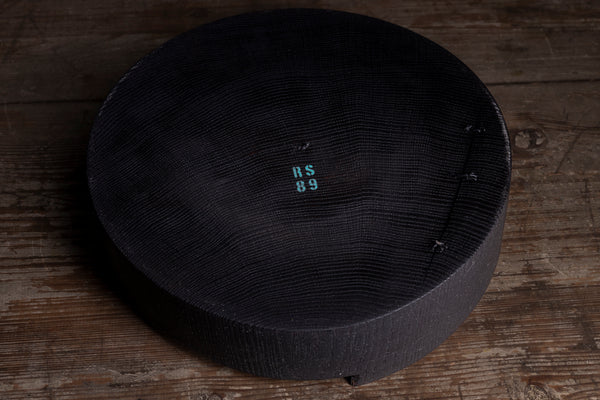 A bottom of a wooden bowl with a natural wood grain edge, shown on a rustic wooden surface.