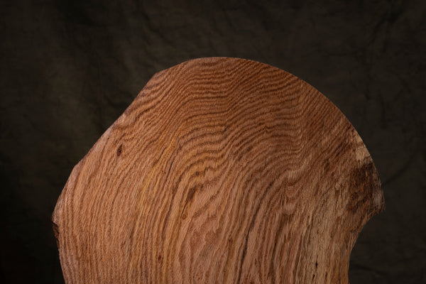 Close-up of a wooden surface of sculptural bowl with visible grain pattern on a dark background