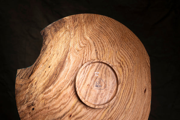 Bottom of sculptural oak bowl photographed against a dark background